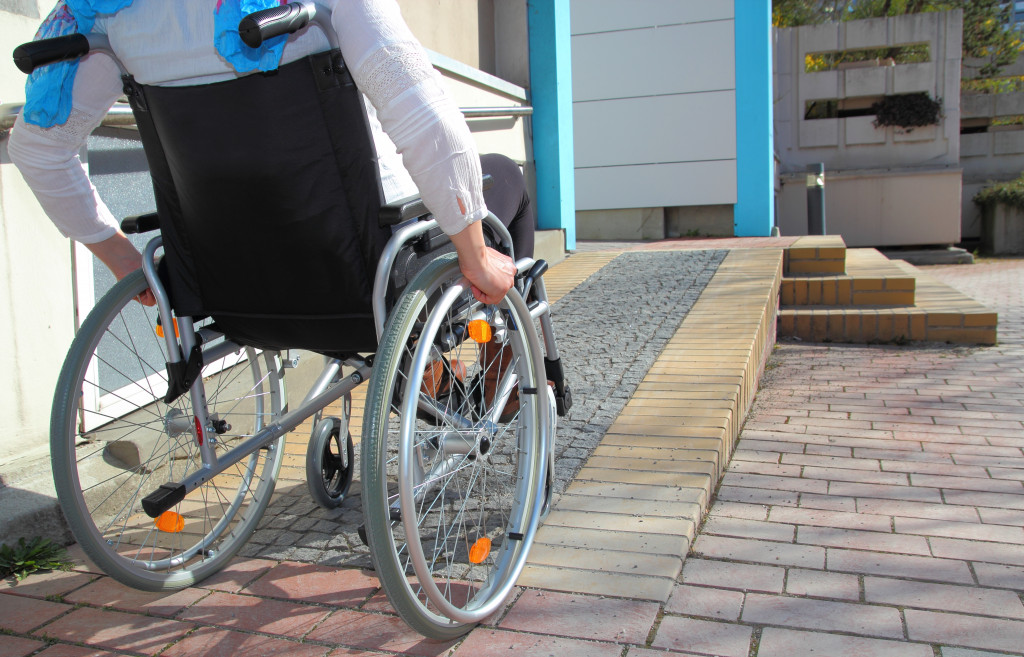 Person on a wheelchair moving up a ramp beside a building.