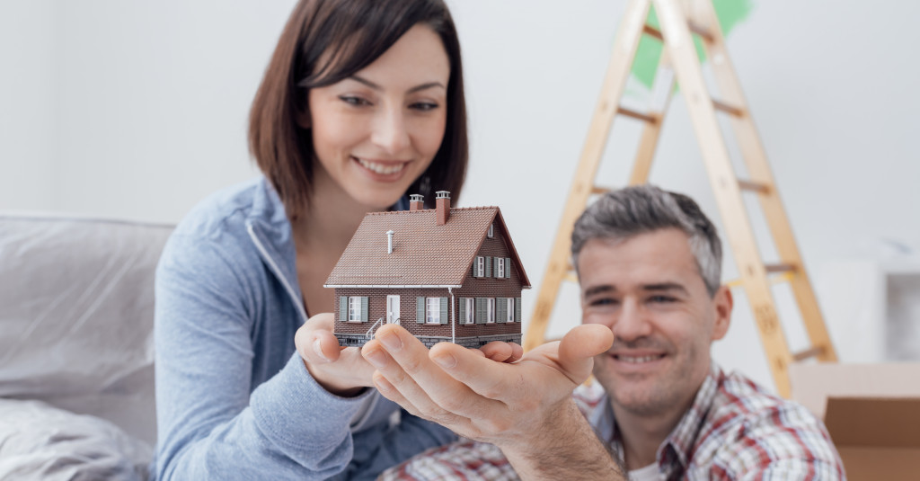 couple smiling holding a house figure